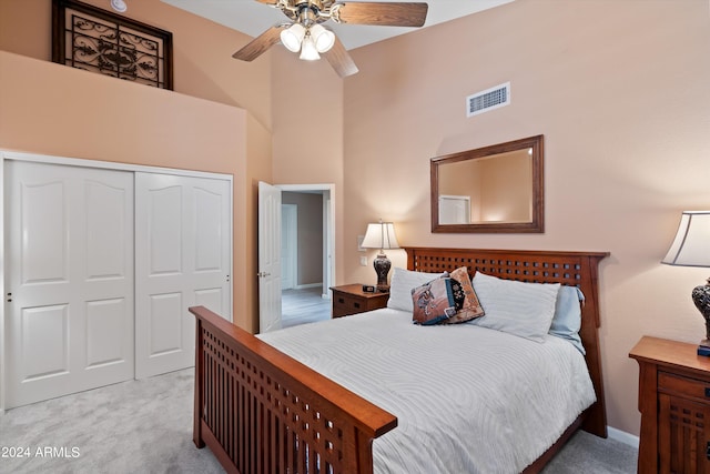 carpeted bedroom with a closet, ceiling fan, and a towering ceiling