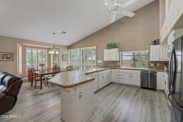 kitchen featuring tile countertops, hanging light fixtures, kitchen peninsula, white cabinets, and appliances with stainless steel finishes