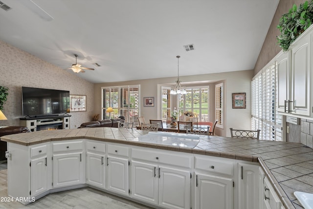 kitchen featuring tile counters, white cabinets, a healthy amount of sunlight, and kitchen peninsula