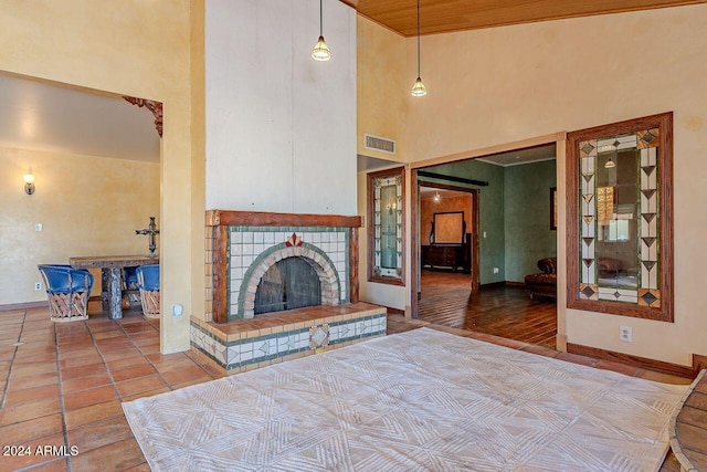 unfurnished living room featuring wood-type flooring, a high ceiling, and a tile fireplace