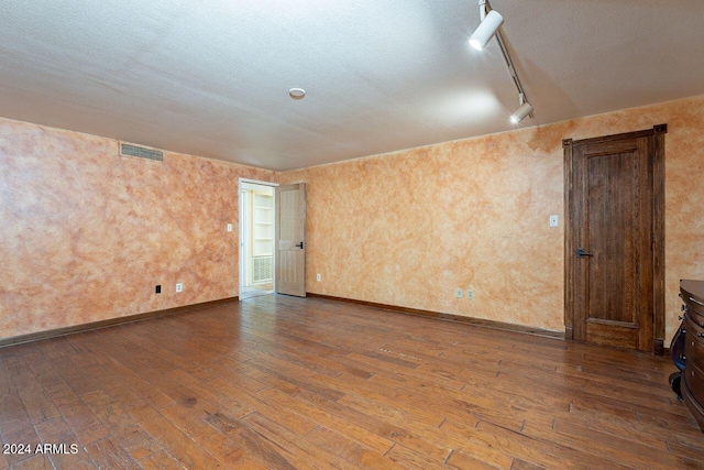 spare room with hardwood / wood-style floors, track lighting, and a textured ceiling