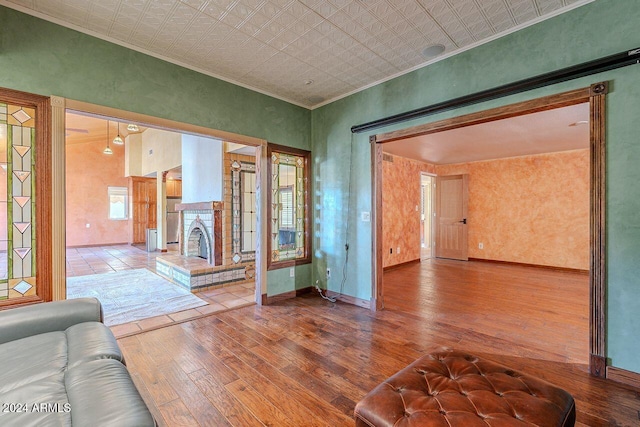 unfurnished living room with hardwood / wood-style floors, a fireplace, plenty of natural light, and ornamental molding