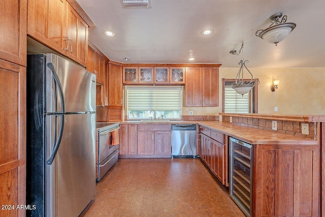 kitchen featuring stainless steel appliances, wine cooler, sink, hardwood / wood-style floors, and pendant lighting