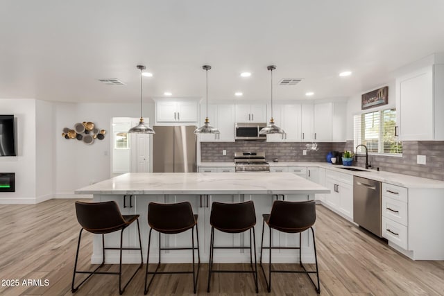 kitchen with appliances with stainless steel finishes, visible vents, a sink, and a kitchen island