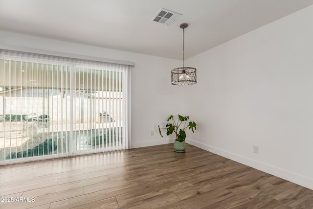 unfurnished dining area with wood finished floors, visible vents, and baseboards