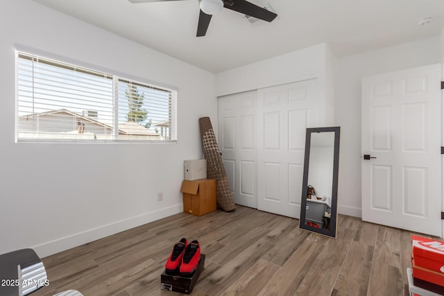 unfurnished bedroom featuring a ceiling fan, a closet, baseboards, and wood finished floors