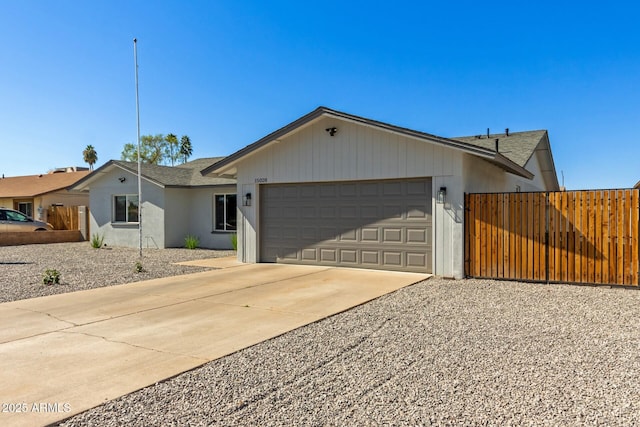 ranch-style home featuring a garage, concrete driveway, and fence