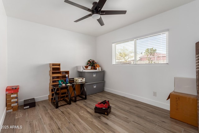 interior space featuring a ceiling fan, baseboards, and wood finished floors