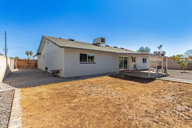 rear view of house featuring a patio, a fenced backyard, roof with shingles, central AC, and stucco siding