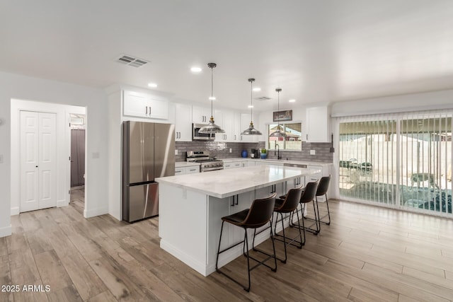 kitchen featuring white cabinetry, visible vents, appliances with stainless steel finishes, backsplash, and a center island