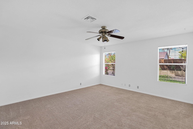 unfurnished room featuring light colored carpet, a ceiling fan, visible vents, and baseboards