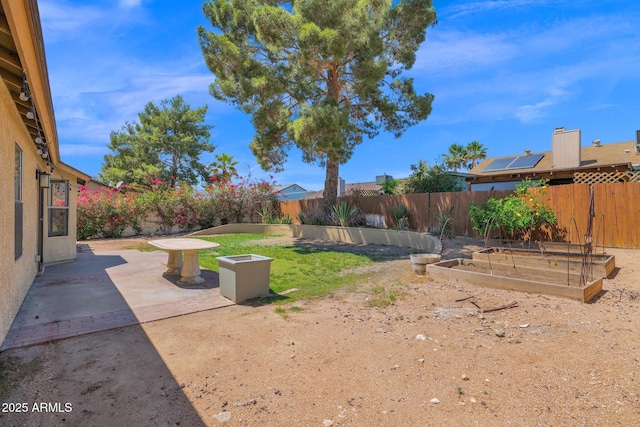 view of yard featuring a fenced backyard, a patio area, and a vegetable garden