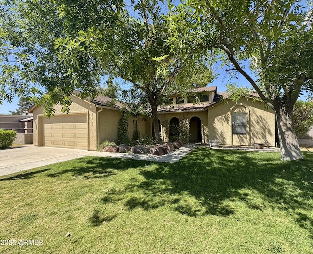 mediterranean / spanish house with an attached garage, stucco siding, a front yard, and concrete driveway