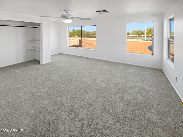 unfurnished bedroom featuring multiple windows, ceiling fan, a closet, and carpet floors