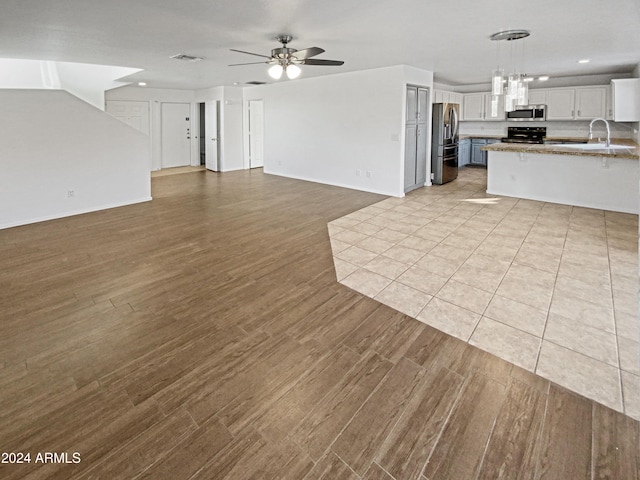 unfurnished living room with ceiling fan, sink, and light hardwood / wood-style floors