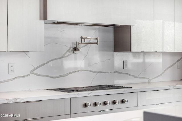 interior details featuring tasteful backsplash, light stone countertops, and white cabinets