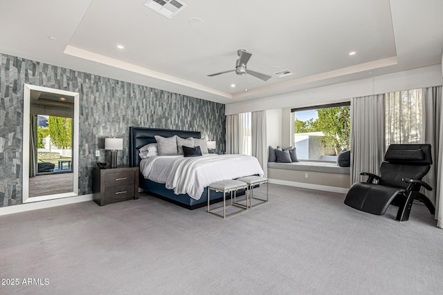 carpeted bedroom featuring ceiling fan and a raised ceiling