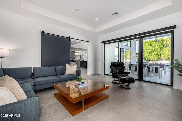 living room featuring a barn door and a raised ceiling