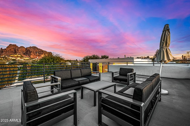 patio terrace at dusk featuring a balcony, an outdoor living space, and a mountain view