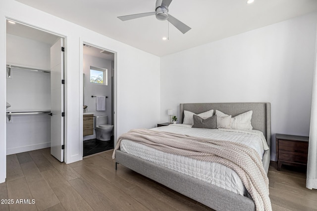 bedroom with connected bathroom, hardwood / wood-style flooring, a spacious closet, ceiling fan, and a closet