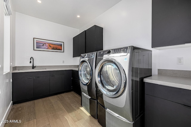 washroom featuring cabinets, light hardwood / wood-style floors, sink, and washing machine and dryer