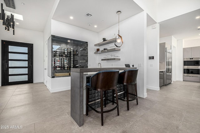 bar featuring stainless steel double oven and decorative light fixtures