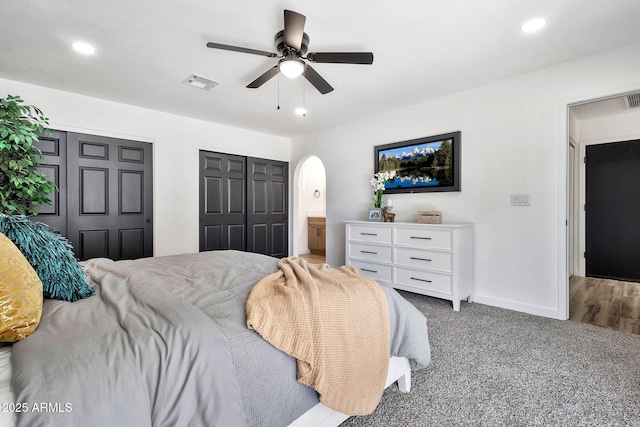 carpeted bedroom with recessed lighting, arched walkways, visible vents, and baseboards