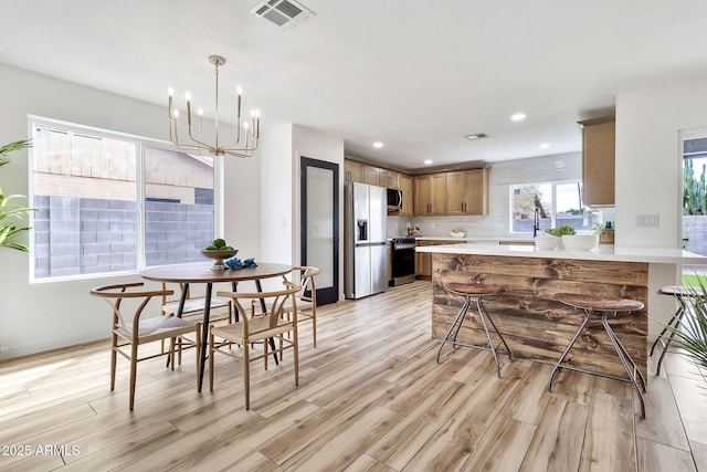 dining area featuring visible vents, light wood-style flooring, recessed lighting, an inviting chandelier, and baseboards