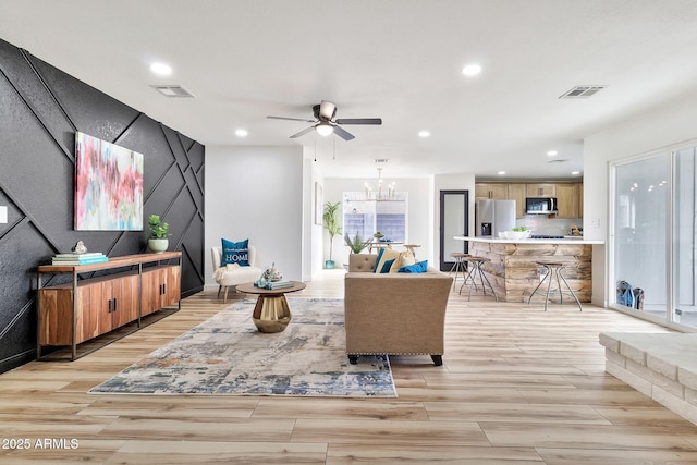 living area with recessed lighting, visible vents, wood finish floors, and ceiling fan with notable chandelier