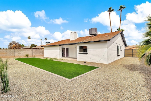 back of house featuring central air condition unit, a lawn, a chimney, a fenced backyard, and a patio