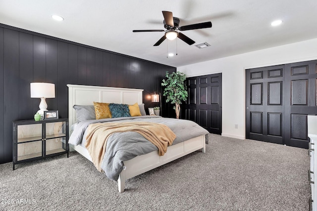 carpeted bedroom featuring recessed lighting, visible vents, multiple closets, and a ceiling fan