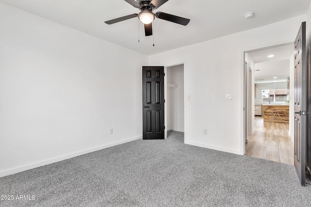 unfurnished bedroom featuring light colored carpet, a ceiling fan, and baseboards