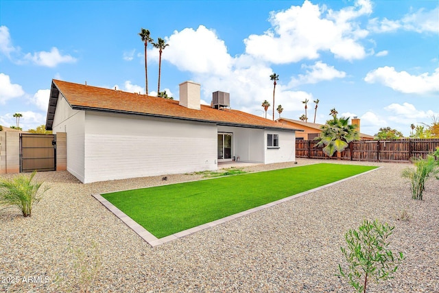 back of property with central air condition unit, a lawn, fence private yard, and a patio