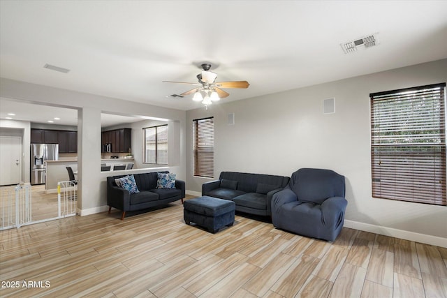 living room featuring ceiling fan, light hardwood / wood-style flooring, and a wealth of natural light