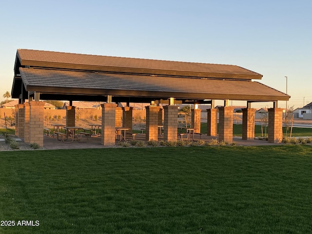 back of house at dusk featuring a lawn