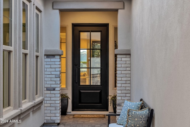 view of exterior entry featuring stone siding, brick siding, and stucco siding