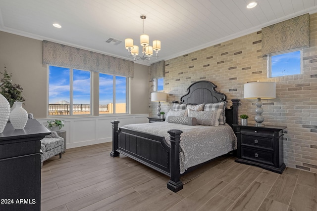 bedroom with visible vents, an inviting chandelier, ornamental molding, wainscoting, and wood finished floors