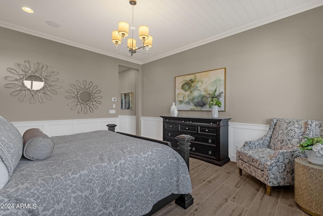 bedroom with crown molding, wainscoting, wood finished floors, and an inviting chandelier