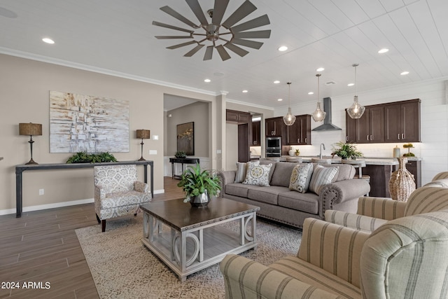 living area featuring ornamental molding, recessed lighting, wood finished floors, and baseboards