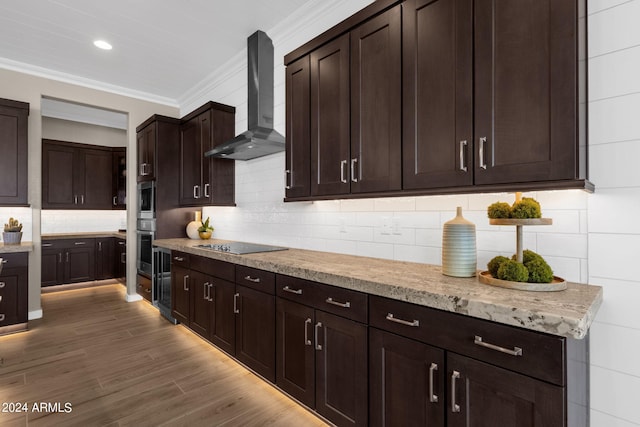 kitchen featuring black electric stovetop, wood finished floors, dark brown cabinets, ornamental molding, and wall chimney range hood