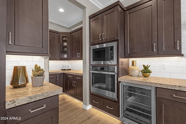 kitchen featuring wine cooler, dark brown cabinetry, stainless steel oven, ornamental molding, and built in microwave