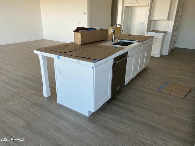 kitchen with decorative backsplash, dishwashing machine, wood finished floors, white cabinetry, and a sink