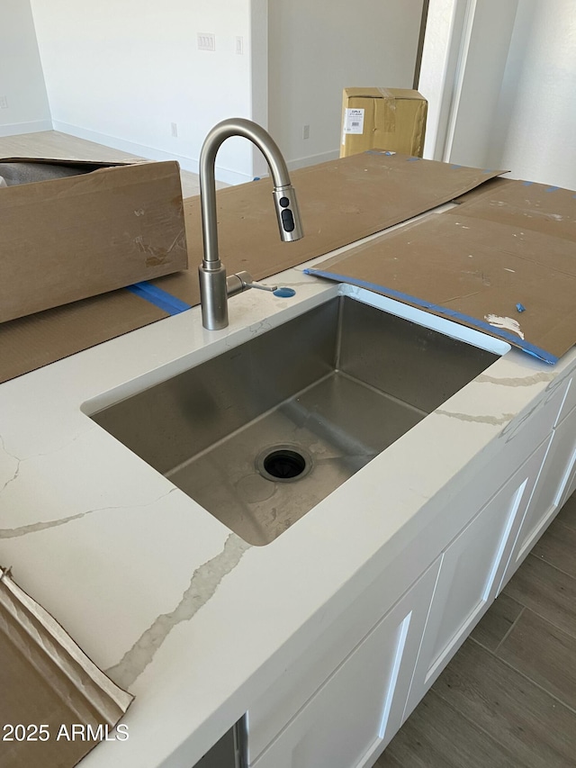 interior details featuring white cabinetry, light stone countertops, and sink