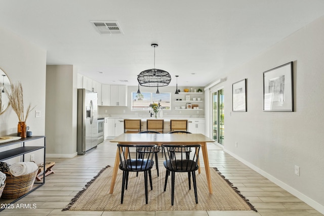 dining space with wood finish floors, visible vents, and baseboards