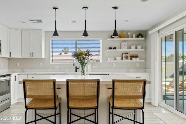 kitchen with a kitchen island, visible vents, white cabinets, open shelves, and a kitchen bar