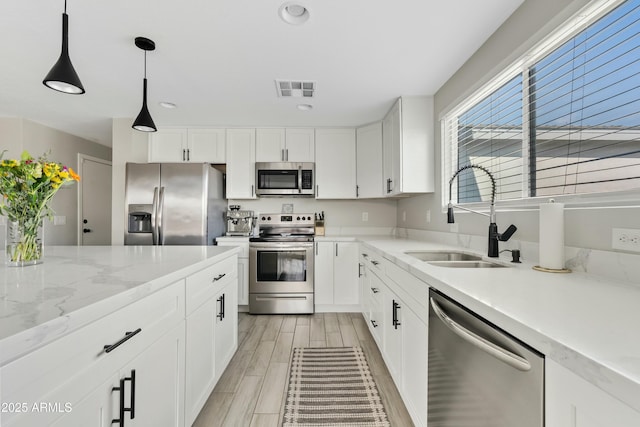 kitchen featuring visible vents, stainless steel appliances, a sink, and white cabinetry