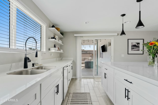 kitchen with decorative light fixtures, open shelves, white cabinetry, a sink, and light stone countertops