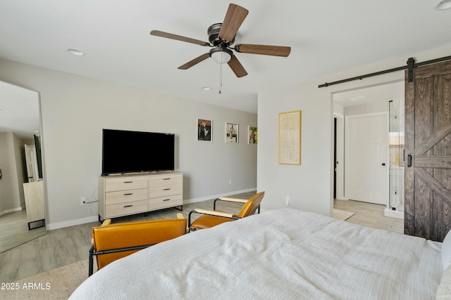 bedroom featuring light wood-style floors, ceiling fan, baseboards, and a barn door