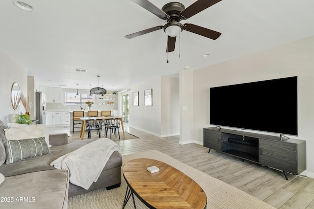 living room with ceiling fan and light hardwood / wood-style floors