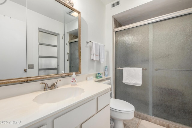 full bathroom featuring vanity, toilet, visible vents, and a stall shower